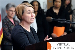 [ai] A woman speaking at a podium during a virtual event series, with a microphone and a banner displaying the event's title in the corner. Several people are visible in the background.